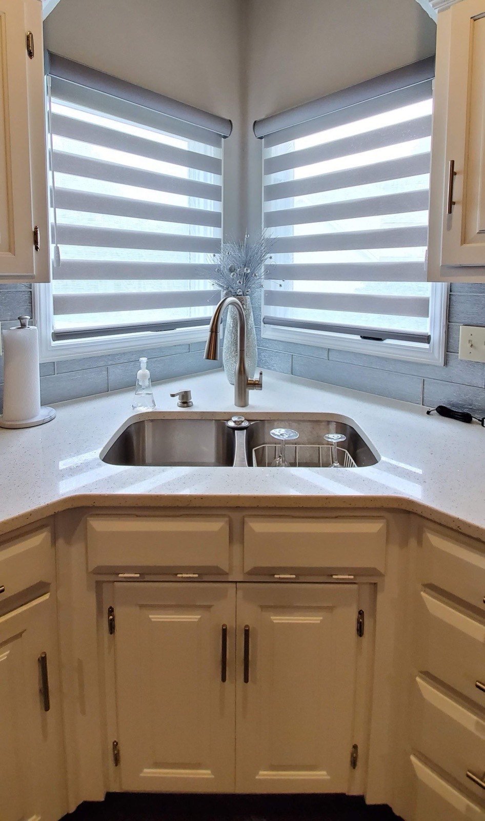 Corner kitchen windows fitted with banded shades above the sink